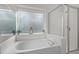 Close up of garden tub with glass shower doors and frosted window at 1322 Pebble Creek Xing, Durham, NC 27713