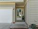 Covered front entrance with neutral siding, white door and potted plants at 1322 Pebble Creek Xing, Durham, NC 27713