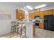 Well-lit kitchen features wooden cabinets, black refrigerator, and a breakfast bar with seating at 1322 Pebble Creek Xing, Durham, NC 27713