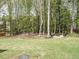 Large backyard with mature trees, lawn, and custom fire pit area with seating at 140 Clear Water Rd, Louisburg, NC 27549