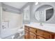 Bathroom features a tub-shower combo, round mirror and wood cabinets at 1433 Andersonwood Dr, Fuquay Varina, NC 27526