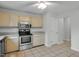 Well-lit kitchen with tile floor, stainless steel appliances, and neutral colored cabinets at 1517 Laughridge Dr, Cary, NC 27511