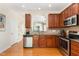 Well-lit kitchen features stainless appliances, wooden cabinets, granite countertops, and tile backsplash at 162 Grey Elm Trl, Durham, NC 27713