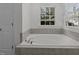 Bright bathroom featuring a tiled soaking tub with a large window at 2 Piney Ridge Ct, Durham, NC 27712