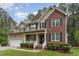 Inviting two-story home featuring a brick facade, black shutters, and a charming front porch with white railings at 2 Piney Ridge Ct, Durham, NC 27712