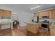 Open kitchen with wood floors, granite island, and stainless steel appliances at 2 Piney Ridge Ct, Durham, NC 27712