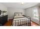 Cozy bedroom with a wrought iron bed frame, wood floors, and natural light from the window at 205 W Moore St, Apex, NC 27502