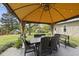 Outdoor dining area under a shaded gazebo with a table, chairs, and backyard view at 205 W Moore St, Apex, NC 27502