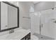 A stylish bathroom featuring a walk-in shower with glass doors, a dark vanity and black and white floor tiling at 2432 Spindle Ct, Raleigh, NC 27603