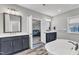 Bright bathroom featuring double vanities, a soaking tub, and an open doorway to the bedroom at 2432 Spindle Ct, Raleigh, NC 27603