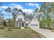 New construction farmhouse with white siding, a two-car garage, black shutters, and a landscaped lawn at 2432 Spindle Ct, Raleigh, NC 27603