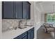 A modern kitchen features a stylish coffee station with blue cabinets, quartz countertops, and decorative tile backsplash at 2432 Spindle Ct, Raleigh, NC 27603