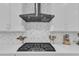 Modern kitchen cooktop with stainless steel range hood and herringbone tile backsplash at 2432 Spindle Ct, Raleigh, NC 27603