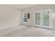 Bright, carpeted living room featuring a window and access to the patio through glass doors at 2604 Wyntercrest Ln, Durham, NC 27713