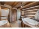 Rustic bathroom with log walls, jacuzzi tub, and charming fixtures; a cozy retreat at 2931 Western Hills Ln, Elon, NC 27244
