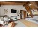Cozy bedroom featuring wood floors, beamed ceilings, TV, and comfortable seating area at 2931 Western Hills Ln, Elon, NC 27244