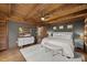Bedroom boasts exposed beams, grey accent wall, and luxurious white bedding with a bench at 2931 Western Hills Ln, Elon, NC 27244