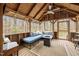 Enclosed porch with wood ceiling, cushioned bench seating and an outdoor gas fireplace at 2931 Western Hills Ln, Elon, NC 27244