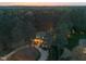 Sunset aerial view of house surrounded by lush trees, with warm lights glowing within at 3016 Allansford Ln, Raleigh, NC 27613