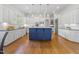 A spacious kitchen featuring a blue island, stainless steel appliances, white cabinets and hardwood floors at 3016 Allansford Ln, Raleigh, NC 27613