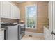 Bright laundry room with a front load washer/dryer, custom cabinets and a view to the outdoors at 3016 Allansford Ln, Raleigh, NC 27613