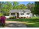 Exterior of a cozy home showcasing a manicured lawn, gravel driveway, and vibrant pink azalea bushes at 304 Westgate Cir, Angier, NC 27501