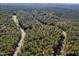 An aerial view of a wooded lot with a road winding through the trees and colorful autumn foliage at 306 White Magnolia Ln, Fuquay Varina, NC 27526