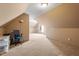 Bright attic featuring neutral carpet, a lamp, and a comfortable office chair, offering potential living space at 310 Cedarhurst Ln, Franklinton, NC 27525