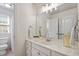 Bright bathroom featuring a marble countertop, white cabinetry and sink, decorative mirror and a window for natural light at 317 Okamato St, Raleigh, NC 27603