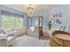 Light-filled Bedroom with a modern crib, comfortable armchair, window view, and soft blue walls at 317 Okamato St, Raleigh, NC 27603