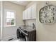Well-lit laundry room with gray washer and dryer, cabinets, window, and stylish decorative floor tile at 317 Okamato St, Raleigh, NC 27603
