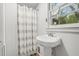 A charming bathroom with a pedestal sink, toilet, and shower with decorative gray and white striped curtain at 323 Coral Ave, Goldston, NC 27252