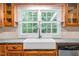 Close-up of a kitchen farmhouse sink with granite countertops, wooden cabinets, and a view of the outdoors at 323 Coral Ave, Goldston, NC 27252