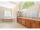 Bathroom featuring dual sinks, cabinets, and a separate tub and shower at 40 Holden Ct, Youngsville, NC 27596