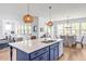 Modern kitchen island with pendant lighting and a view into the dining area with large windows at 490 Boulder Point Dr, Chapel Hill, NC 27516