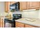 A well-equipped kitchen features wood cabinetry, black appliances, and neutral countertops at 507 Presque Isle Ln # Bldg 500, Chapel Hill, NC 27514