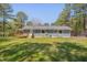 Backyard view featuring a well-kept lawn, mature trees, deck, and the exterior of the home at 5604 Bobcat Rd, Chapel Hill, NC 27516