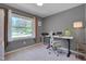Bright office space featuring gray walls, white desk with laptop, and view of the front yard from the large window at 5604 Bobcat Rd, Chapel Hill, NC 27516