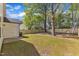Fenced backyard with mature trees, green grass, and the house's utility door at 617 Ray St, Selma, NC 27576