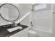Bathroom features a modern black granite vanity, round mirror, and shower-tub combination at 619 Ray St, Selma, NC 27576