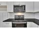 Stainless steel oven and microwave with modern white cabinetry and dark countertops at 619 Ray St, Selma, NC 27576