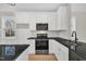 Well-lit kitchen with white cabinets, black countertops, stainless appliances, and wainscoting at 619 Ray St, Selma, NC 27576