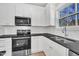 Well-lit kitchen features stainless steel appliances, white cabinets, and a double bowl sink beneath a window at 621 Ray St, Selma, NC 27576