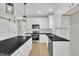 Open kitchen features stainless steel appliances, white cabinets, black countertops, and a center island with pendant lighting at 621 Ray St, Selma, NC 27576