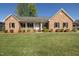 Charming brick home featuring a well-manicured lawn, covered front porch, and mature landscaping at 627 Carraway Dr, Graham, NC 27253