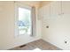 Bright laundry room with window, overhead storage cabinets, and tile flooring at 627 Carraway Dr, Graham, NC 27253