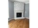 Cozy living room featuring a white stone fireplace, hardwood floors, and a large window at 6283 Harrisontown Rd, Rocky Mount, NC 27804