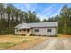 Charming single-story home featuring gray siding, black shutters and a covered front porch set on a large wooded lot at 6312 Briddle Dr, Wendell, NC 27591