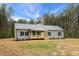 Single-story home with gray vinyl siding, black shutters, a covered porch, and mature trees, creating a serene setting at 6312 Briddle Dr, Wendell, NC 27591
