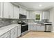 Modern kitchen featuring stainless steel appliances, white cabinetry, and a grey mosaic backsplash at 6312 Briddle Dr, Wendell, NC 27591